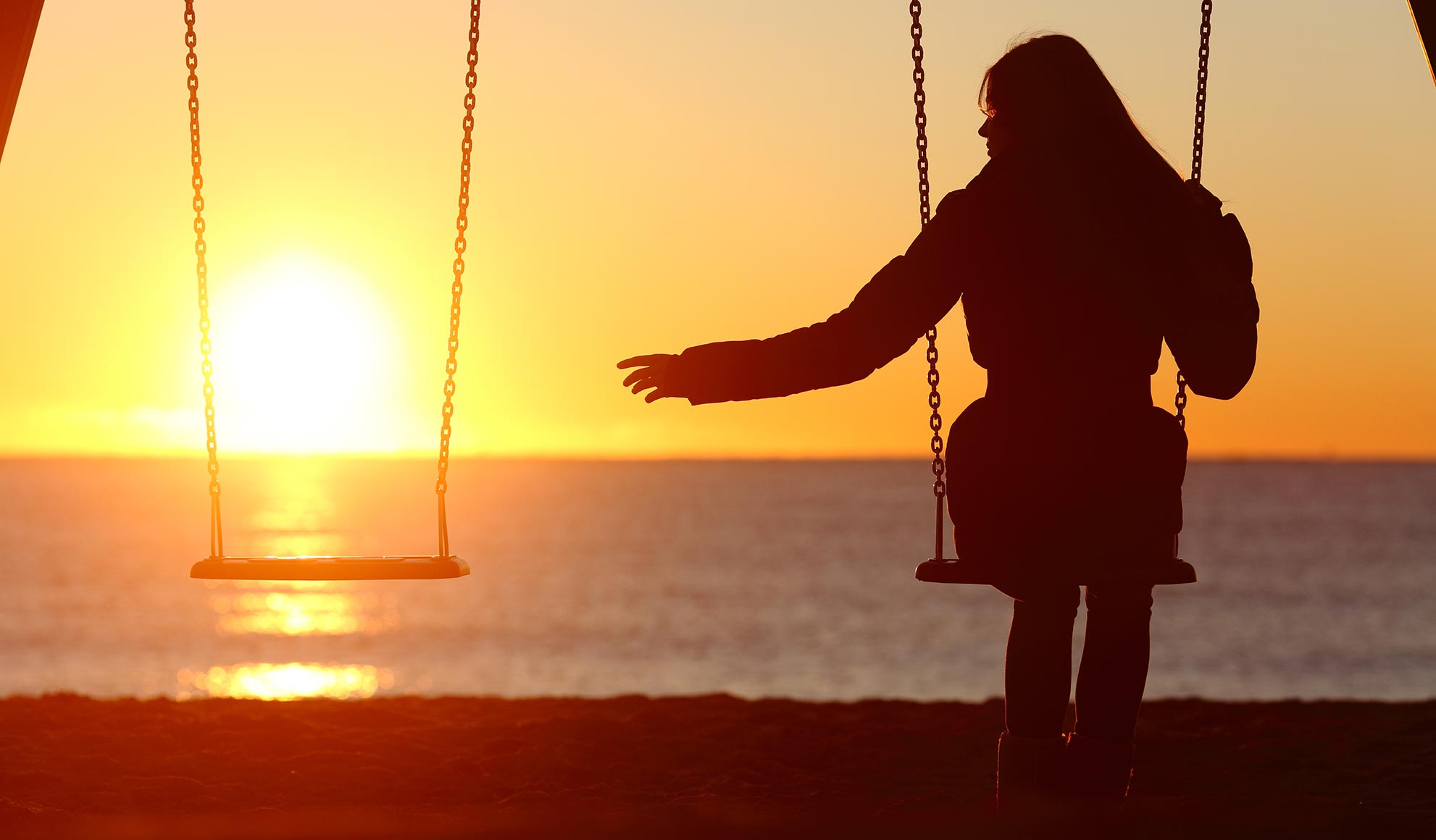 sitzenden Frau auf einer Schaukel beim Sonnenuntergang